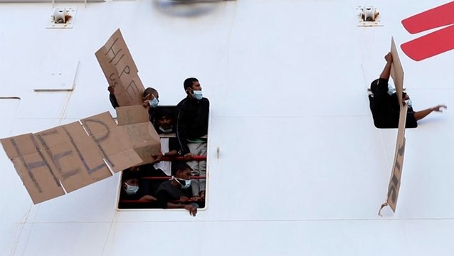 Migrants wave signs reading ‘help’ from windows of rescue ship after being blocked from disembarking