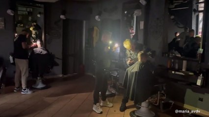 Num país às escuras, ucranianos usam lanternas do telemóvel em barbearia