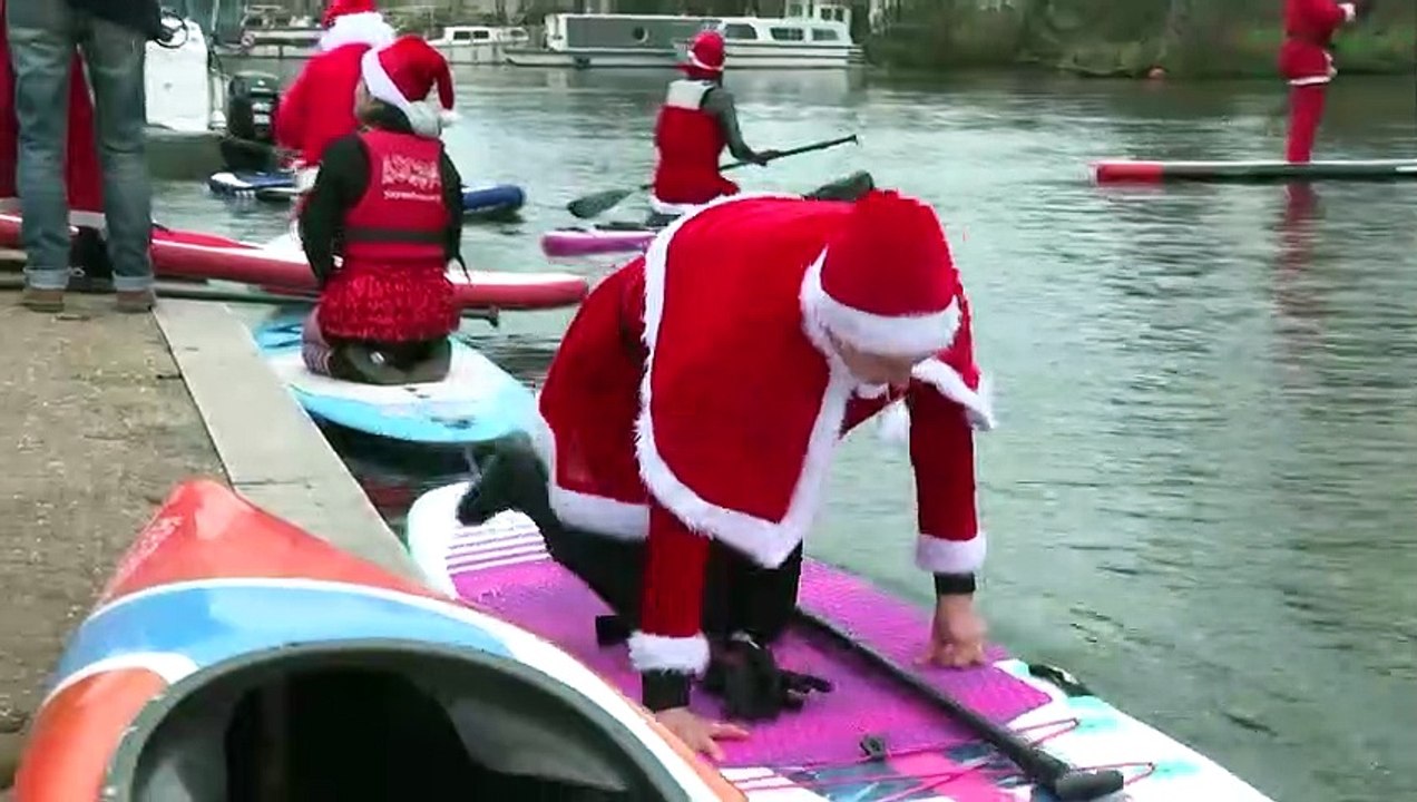 Weihnachtsmänner auf SUP-Boards fahren durch Straßburg