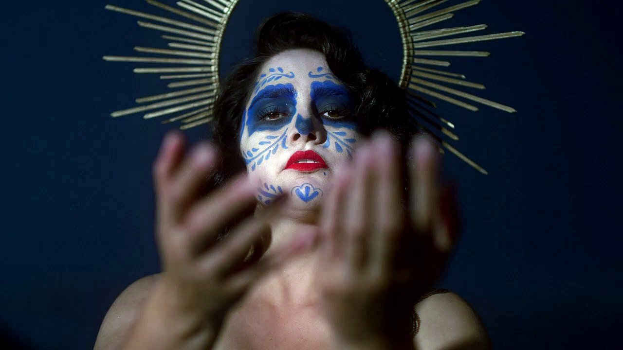 Seorang - wanita - dengan - wajah - penuh - gambar - dan memegang - lilin -mixkit-face-of-a-catrina-on-the-night-of-the-day-44256-medium