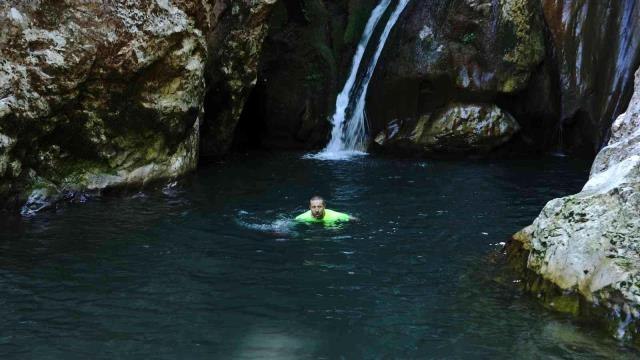 Doğa harikası şelaleleri tanıtmak için soğuk havaya aldırış etmeden buz gibi suda yüzdü