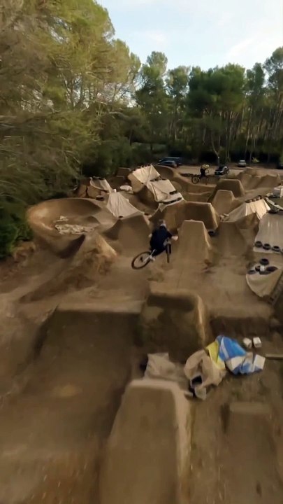 Group of Mountain Bike Riders Jump Over Mud Ramps