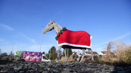The Horsforth A65 'The White Horse' sculpture wearing it's red Christmas coat, Christmas garland, and Santa hat for all motorist to see as they drive by
