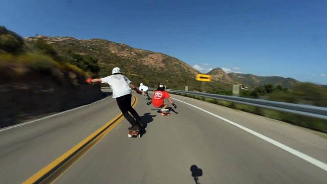 Longboarders ride downhill and one crashes into another rider