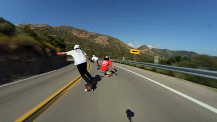 Longboarders ride downhill and one crashes into another rider