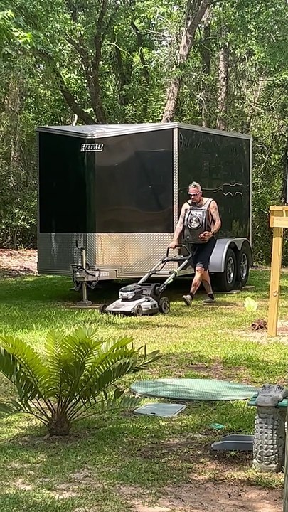 Man Mows Lawn While Carrying Cat in Backpack