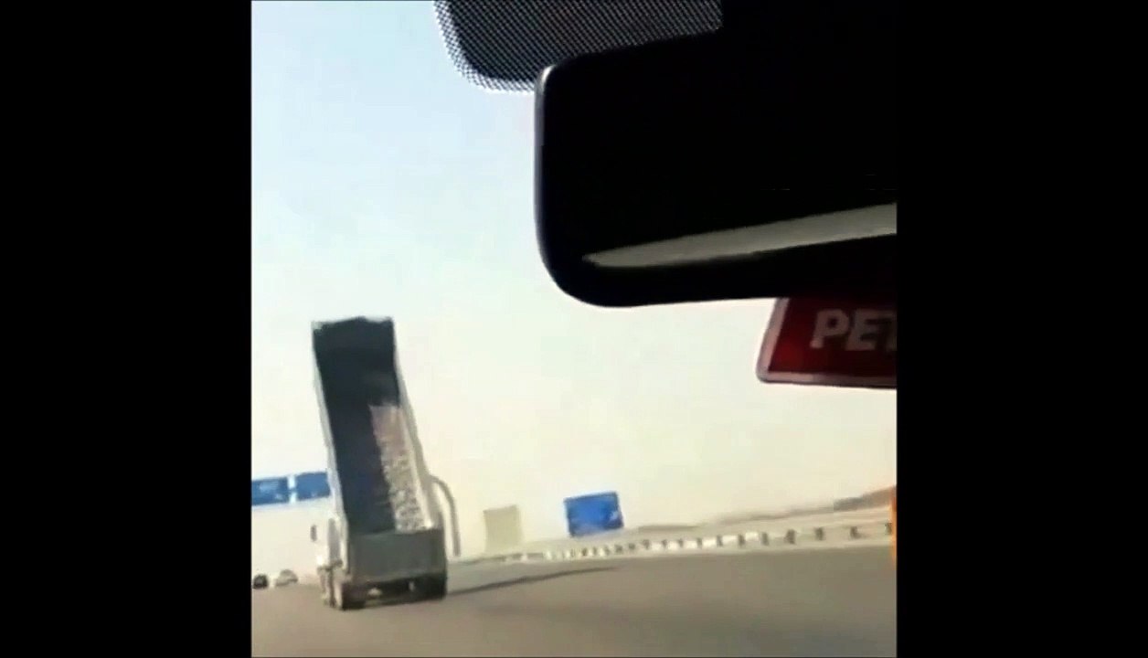 Un camion avec la remorque levée passe sous un pont sur l'autoroute