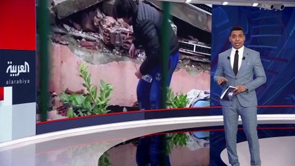 شخص ينزل زجاجة ماء مربوطة بخيط لمساعدة محاصرين تحت أنقاض زلزال تركيا