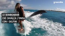 Lo skimboarder che cavalca l'onda con i delfini