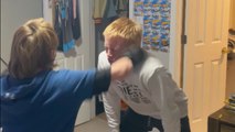 Chill big brother lets young brother practice his punch on him while their dog watches