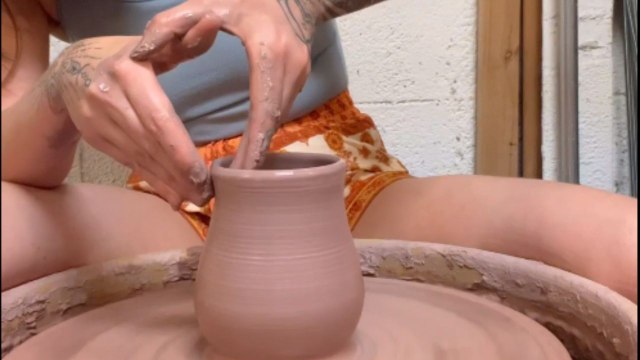 Excited ceramic artist throws on the pottery wheel and makes an elegant cup *Satisfying*