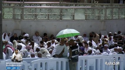 رجل أمن بالمسجد الحرام يحمي معتمراً من حرارة الشمس خلال خطبة أول جمعة برمضان