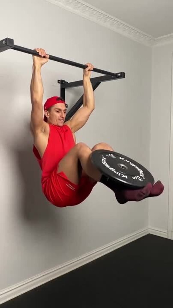 Guy Performing L-sit on Pull Up Bar Flips Weight Plate With Legs