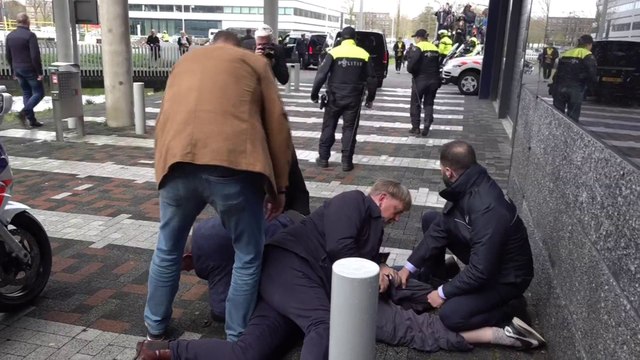 Un homme crie On est là, on est là à l'arrivée d'Emmanuel Macron à l'université d'Amsterdam avant d'être plaqué au sol