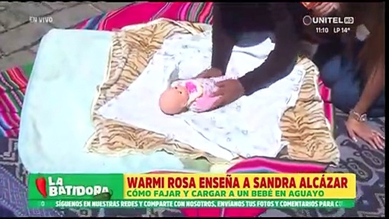 “Hay que saber envolver al bebé”, La Warmi Rosa le enseñan a Sandra Alcázar a cargar en aguayo a un bebé