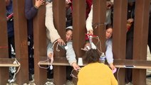 Migrants charge phones through gaps of 30ft fence on US border