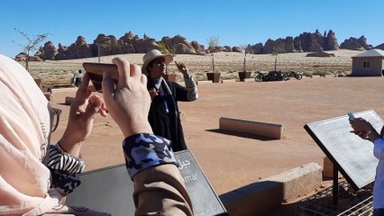 A woman briefing tourists on the history of Madain Saleh Al-Ula.