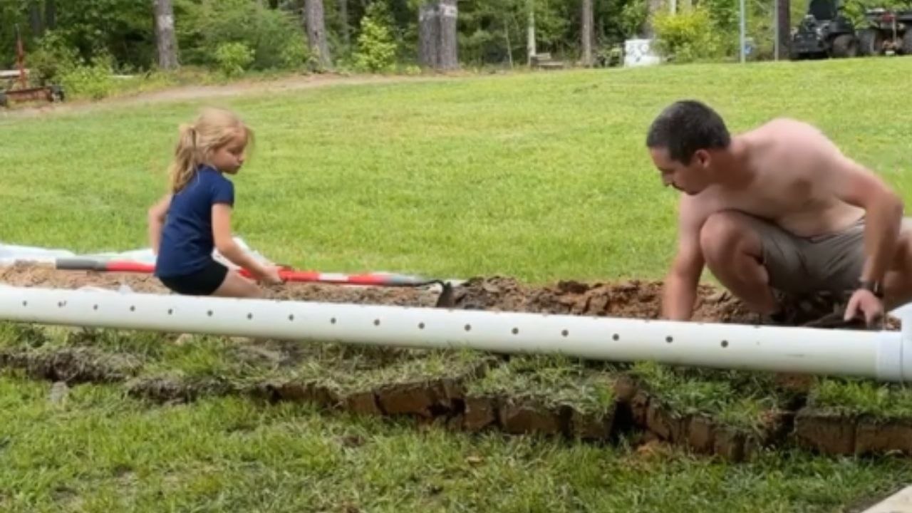 Little girl is daddy's best helper when it comes to digging trenches ...