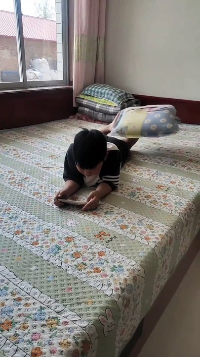 中國一小男孩邊看手機邊用腳轉枕頭！ A Chinese boy swivels his pillow with feet while looking at phone!