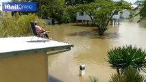 Hombre bebe cerveza y pesca desde su azotea de su casa inundada