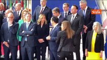 Meloni e Macron al Consiglio Ue si salutano con un bacio sulla guancia dopo la foto di gruppo