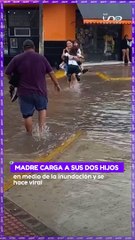 Download Video: Madre carga a sus dos hijos en medio de la inundación y se hace viral.