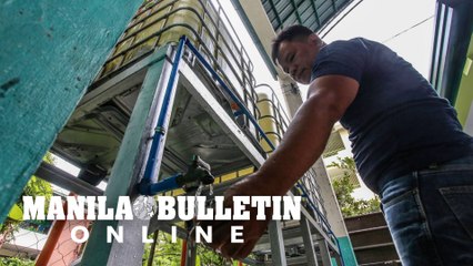 Utility personnel inspects rain catcher containers for supply