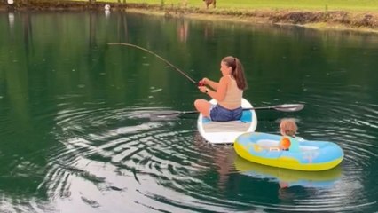 Women fishing with her toddler in the middle of the pond catches a fish