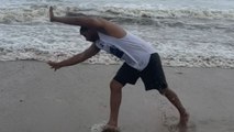 Confident beachgoer's back handspring attempt meets a slippery setback