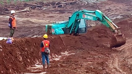 Excavator working build safety berm for mining hauling road