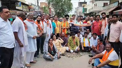 सड़क पर बने गडढ़ों पर धरना देकर जताया विरोध