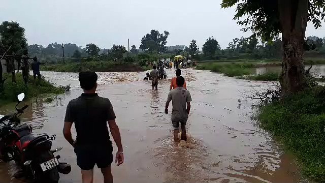 जान जोखिम में डालकर उफनते नाले को पार कर रहे राहगीर