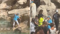 Una turista se sube a la Fontana di Trevi para llenar su botella de agua
