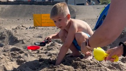Enthusiastic boy's face lights up with sheer joy after finding treasure chest buried in beach sand