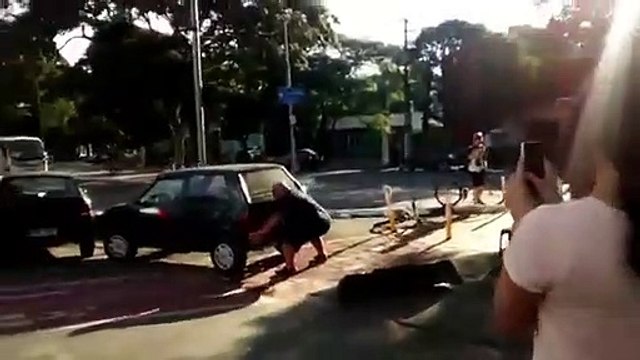Il déplace à mains nues une voiture garée sur une piste cyclable
