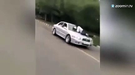 Il roule avec un policier sur son capot