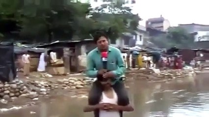 Un journaliste monte sur les épaules d'un rescapé pour ne pas se mouiller