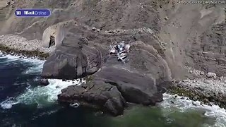 Drone footage shows collapsed driftwood home perched on cliff