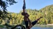 Trio of Men Create Balancing Acrobatic Formation With Each Other on Bank of Scenic River