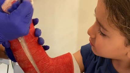 Young boy sits bravely while the medical professional take off his arm cast