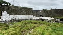 Sandbags used as a temporary solution to a sinkhole on Tanybwlch beach, Aberystwyth, strewn across riverbank