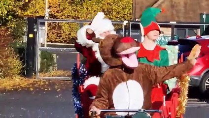 Father Christmas arrives on a  motor mower to the surprise of school children