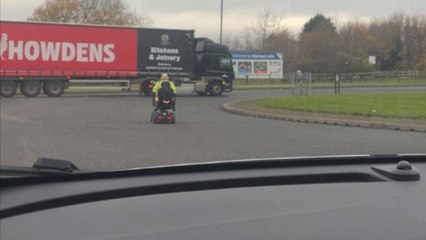 Carefree elderly gentleman zooms around a roundabout on his mobility scooter