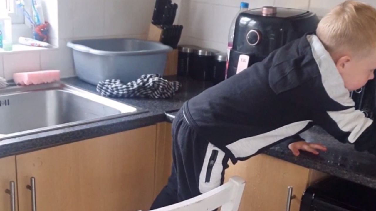 Little boy helps his tired mum by cleaning the kitchen counters *Wholesome*