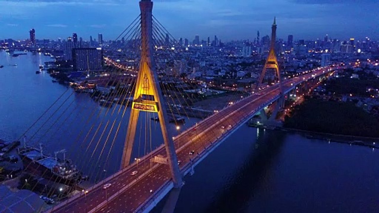 Drone shot during early evening on lighted up Bhumiphol Bridge and river in Bangkok.