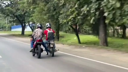 Captan a dos motociclistas platicando mientras conducían