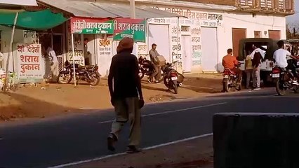 शराब दुकान से पेटियां लेकर जीप में रखते हुए