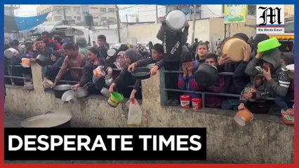 Palestinians wait with containers for food distribution in Rafah