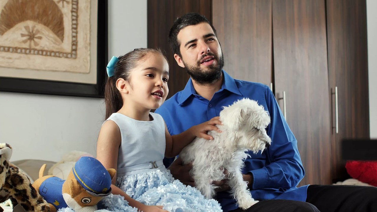 father and daughter together watching television with their little dog
