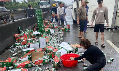 Xe tải lật ngang, hàng trăm thùng bia đổ tràn ra đường